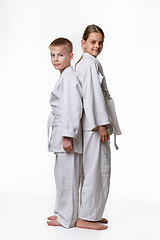 Image showing Boy and girl in sports kimono stand with their backs to each other