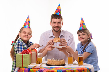 Image showing Dad puts the birthday cake on the plates for children