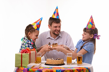 Image showing Dad and two daughters fight for the first piece of the holiday cake