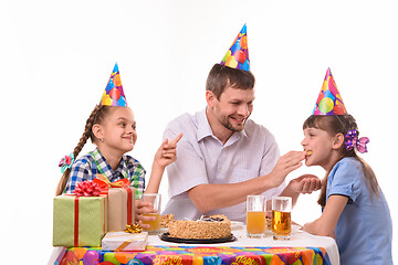 Image showing Dad fun stuffing a piece of cake in his daughter\'s mouth