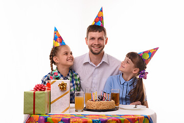 Image showing Two girls happily look at dad at the festive table