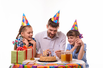 Image showing Dad lights candles on a birthday cake