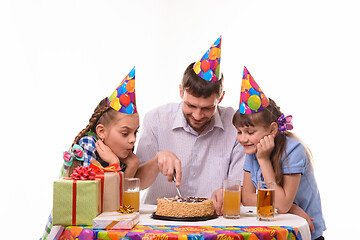 Image showing Dad and two daughters cut a birthday cake with a knife