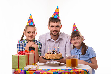 Image showing Dad and two daughters with a holiday cake at the table happily look at the frame