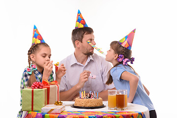 Image showing Girl got into the eyes of dad blowing a festive pipe at a birthday party