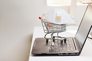 Image showing Conceptual photo with miniature shopping-cart and protecting mask. Safety internet shopping
