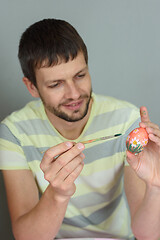 Image showing Man paints an Easter egg with a brush
