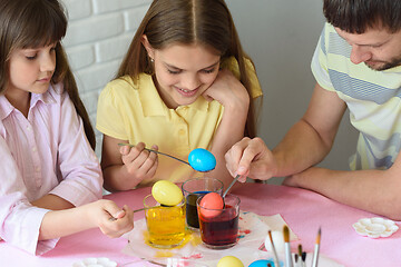 Image showing Daddy paint eggs in glasses with colorful dyes.