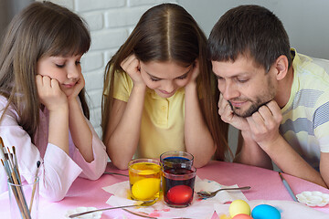 Image showing Dad and two daughters are watching how the eggs are painted in glasses with dyes