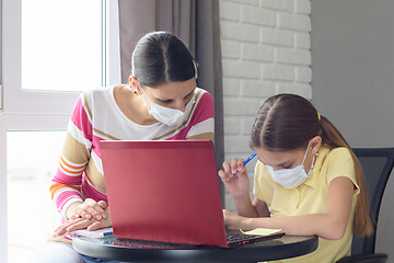 Image showing In quarantine, mom helps the girl complete her homework