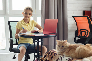 Image showing Schoolgirl at table at home studying remotely online