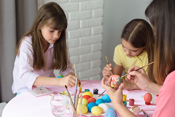 Image showing Mom and daughters enthusiastically paint Easter eggs at home