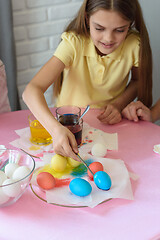 Image showing Girl paints Easter eggs in a special solution and puts on a plate