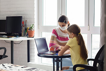 Image showing Mom helps daughter do homework, both in medical protective masks