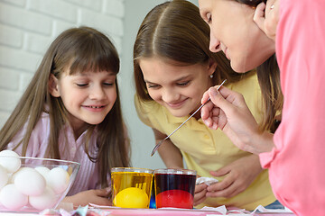 Image showing Family fun watching how the eggs are painted in a solution with dyes