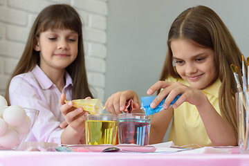 Image showing Sisters pour dye for coloring eggs in a glass of water