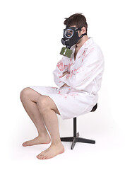 Image showing Man wearing gas mask and bloody doctors coat sitting on small ch