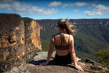 Image showing Woman relaxing on a cliff with scenic views