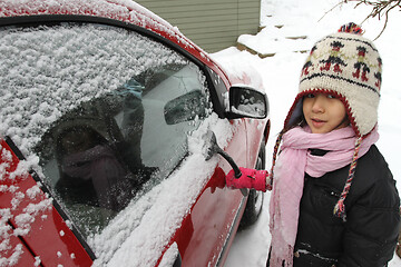 Image showing Portrait of a young cute girl looking at the camera romoving sno