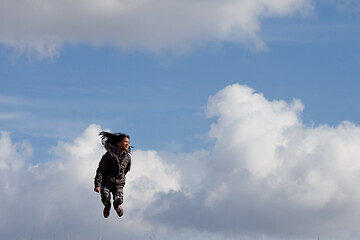 Image showing Cute girl running jumping at the on a field in the summer