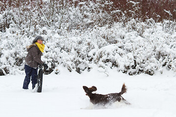 Image showing Girl playing with her dog in the snow