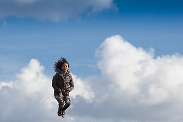 Image showing Cute girl running jumping at the on a field in the summer