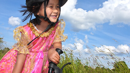 Image showing Cute girl cycling with a princess outfit
