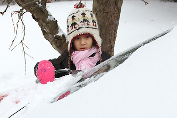 Image showing Portrait of a young cute girl looking at the camera romoving sno