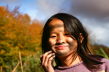 Image showing Portrait of a young cute girl looking at the camera putting coal