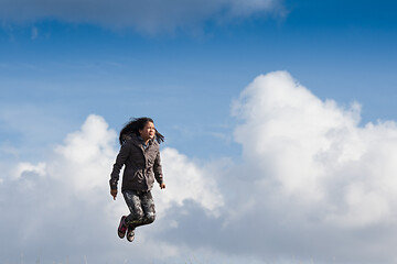 Image showing Cute girl running jumping at the on a field in the summer