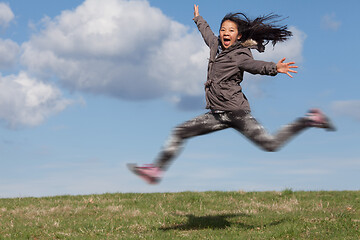 Image showing Cute girl running jumping at the on a field in the summer