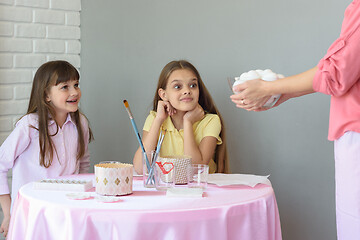 Image showing Mom brought a large plate with eggs to the girls on the table, for their subsequent painting by Easter