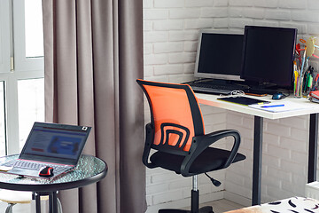 Image showing Part of the interior of the room, on the table is a laptop, in the background is a workplace at home