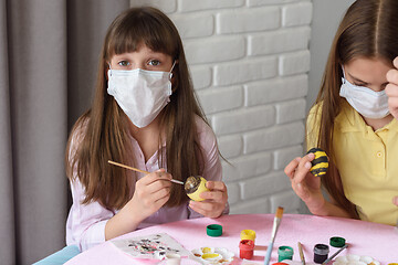 Image showing A sick quarantined child paints Easter eggs for the holiday