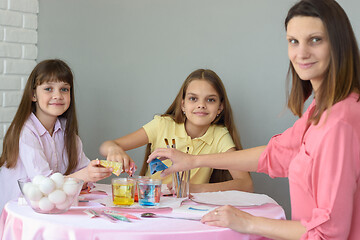 Image showing Mom and two daughters put dye in glasses with water