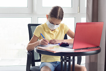 Image showing A girl with a virus gets distance education at home and writes in a notebook