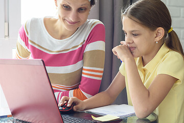 Image showing Girl and girl with a smile look at the laptop screen when they see something funny