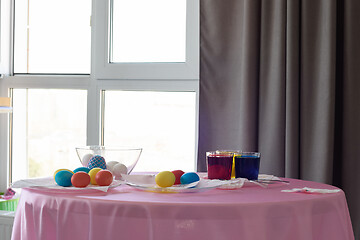 Image showing Table with colorful Easter eggs and dyes in the interior of the room by the window