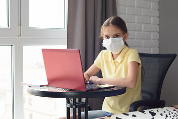 Image showing A sick girl sits at a table and is engaged in learning online, looked into the frame
