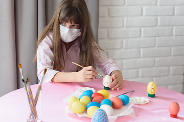 Image showing Sad sick quarantined girl paints Easter eggs