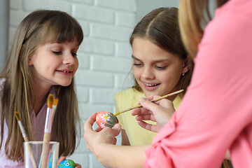 Image showing Children watch mom paint Easter eggs beautifully