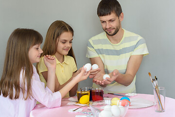 Image showing Dad and daughters sit at the table and paint eggs for Easter