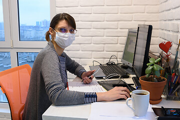 Image showing An ill girl in a medical mask in self-isolation works remotely, looked into the frame
