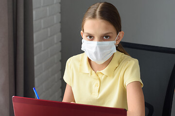 Image showing Girl in medical mask studying at a laptop at home