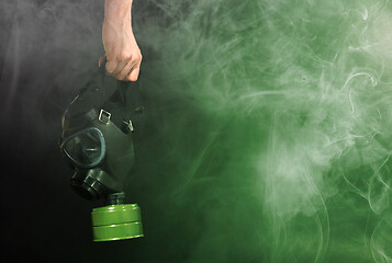 Image showing Man in room filled with smoke, holding a vintage gasmask - Green