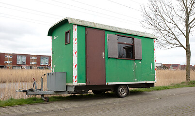 Image showing Old green wooden trailer on wheels stands at the side of the roa