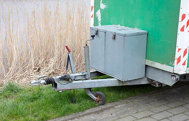 Image showing Old green wooden trailer on wheels stands at the side of the roa