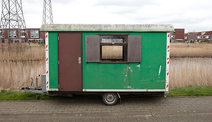 Image showing Old green wooden trailer on wheels stands at the side of the roa