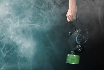 Image showing Man in room filled with smoke, holding a vintage gasmask - Blue 