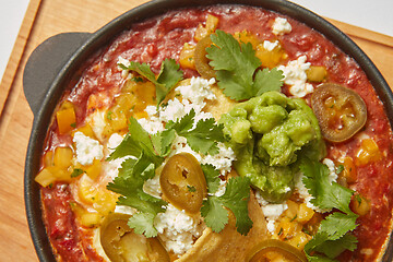 Image showing Close up view of Shakshuka dish in a pan with spicy sauce from tomatoes.